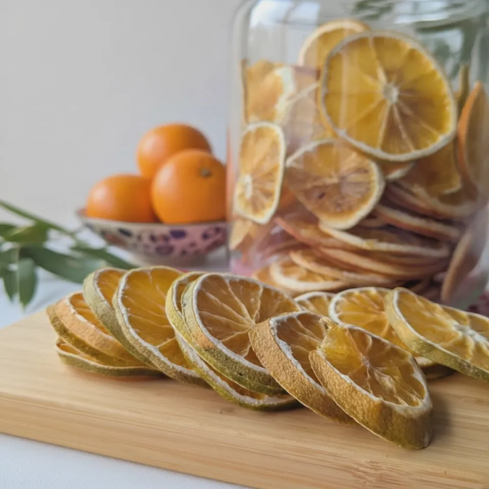 Rodajas de naranja deshidratada con naranjas frescas detrás
