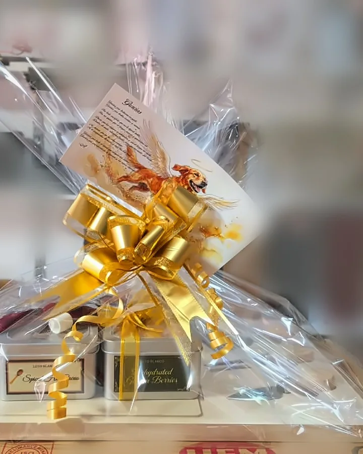 Ancheta en celofán con moño dorado, latas de chocolate caliente y uchuvas, y tarjeta con poema