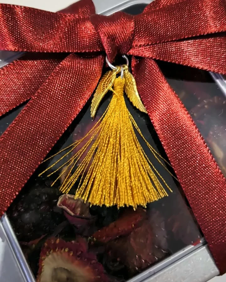 Lata de infusión de frutos rojos con moño vinotinto y dije de alas con borla dorada